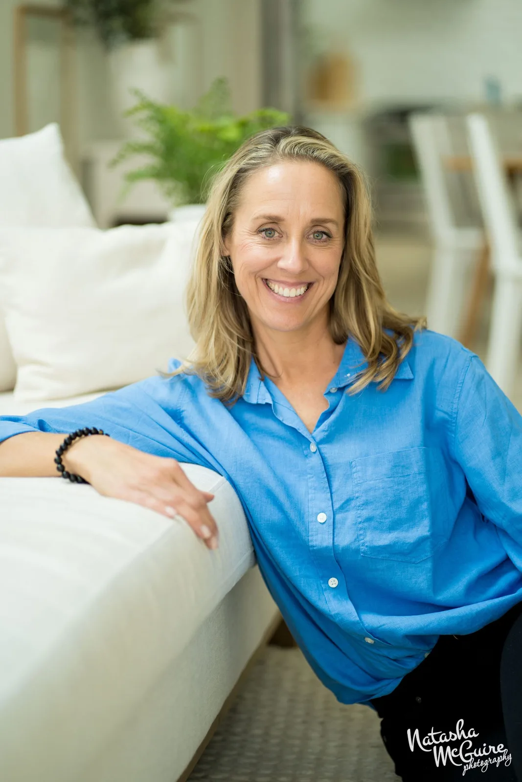 Laura Burkey seated beside a bright window, looking directly at the camera