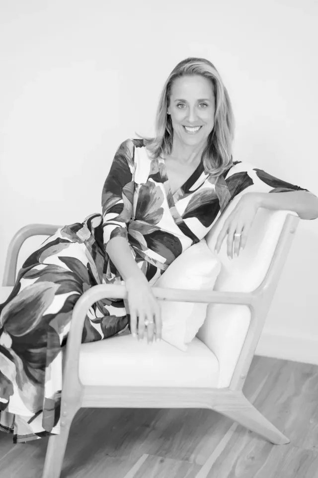 Laura Burkey seated in a patterned chair in a black-and-white portrait