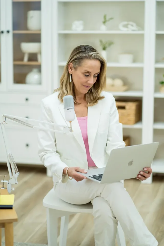 Laura Burkey working at a laptop beside a microphone