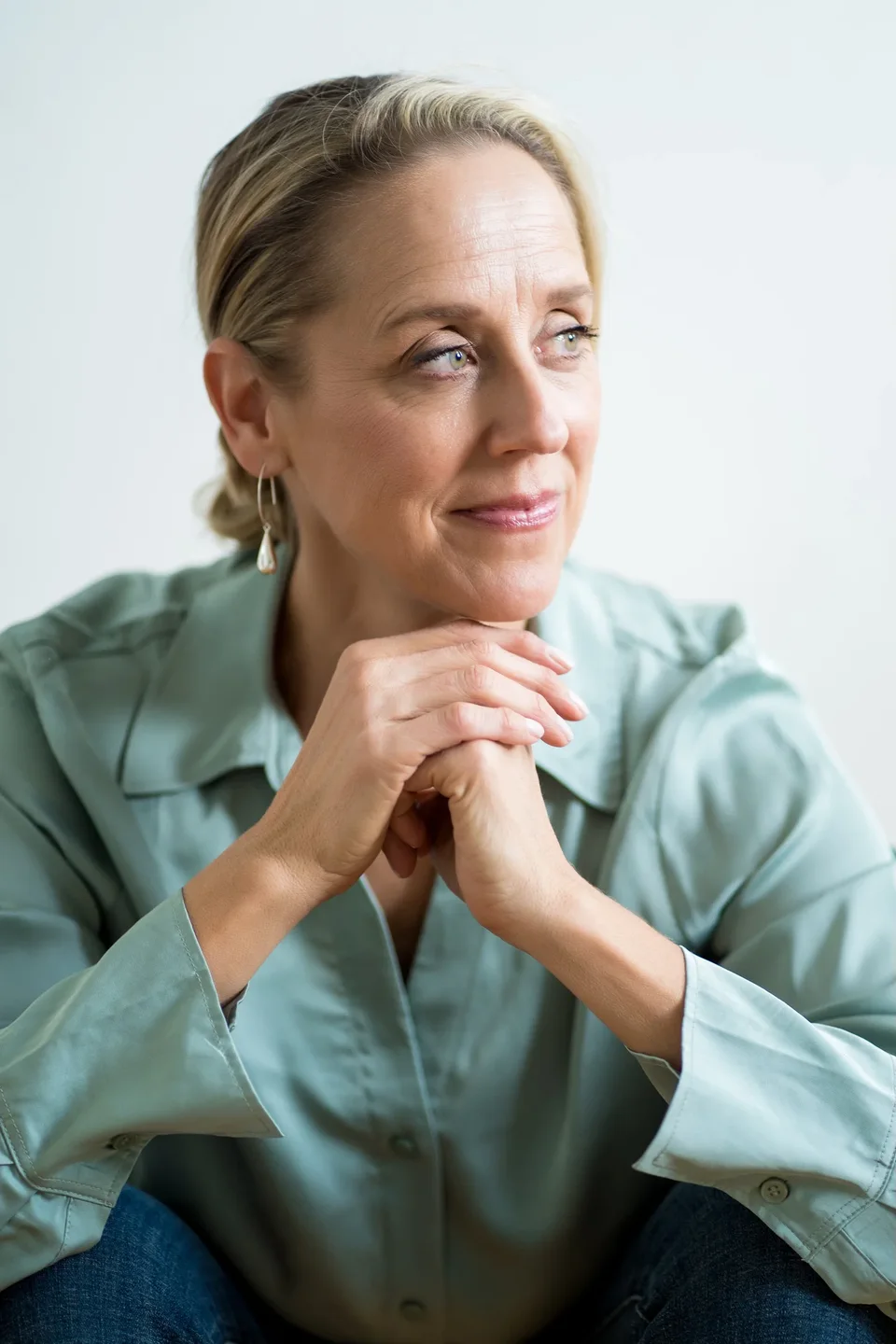 Laura Burkey in a pale green shirt, listening with her hands beneath her chin
